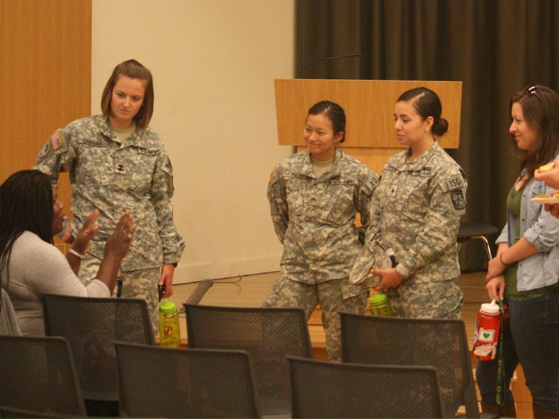 3 Women Veterans in U.S. Army fatigues in lecture hall.