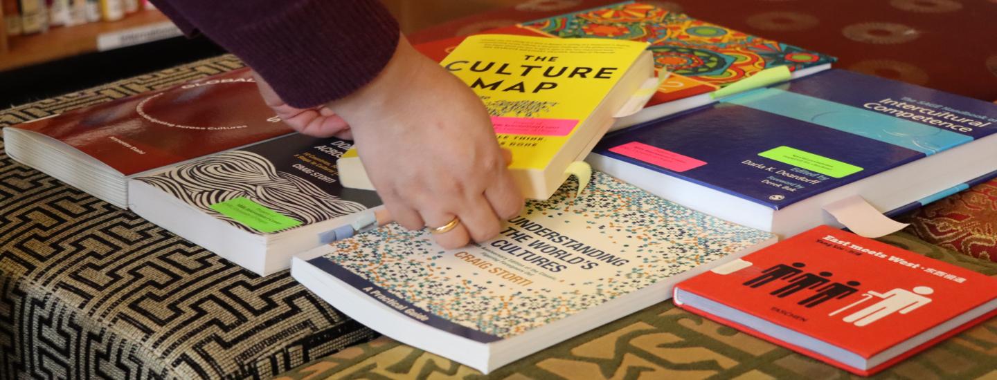 Hands picking up one of many books at the Mills Center