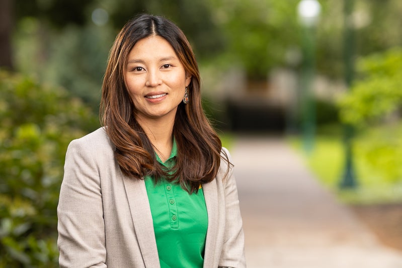 Amy Davies wearing a bright green "O" branded polo shirt and a cream jacket