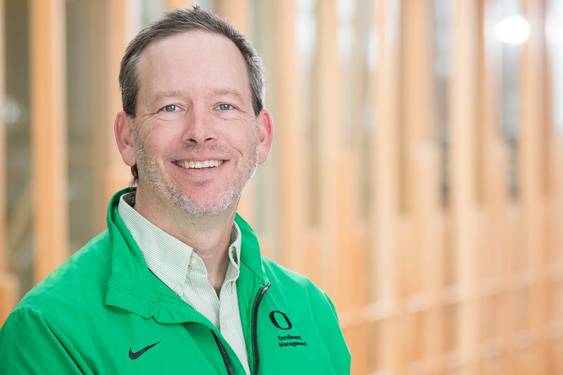 Michael Thompson standing in front of a wood paneled wall in a green pullover