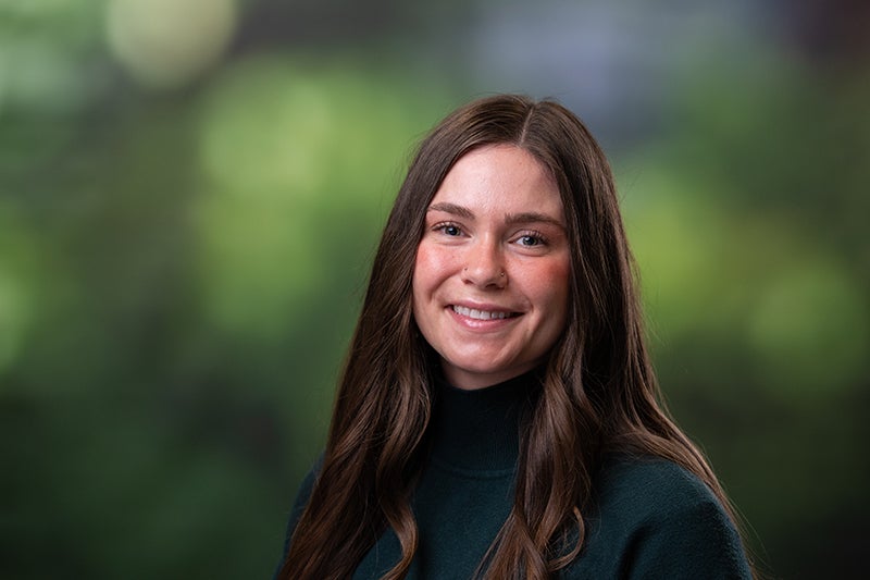 Woman with long brown hair wearing a dark green sweater