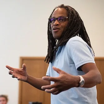 ulrick casimir gesturing while teaching at the front of a classroom