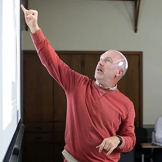 christopher michlig pointing at the board as he teaches a class