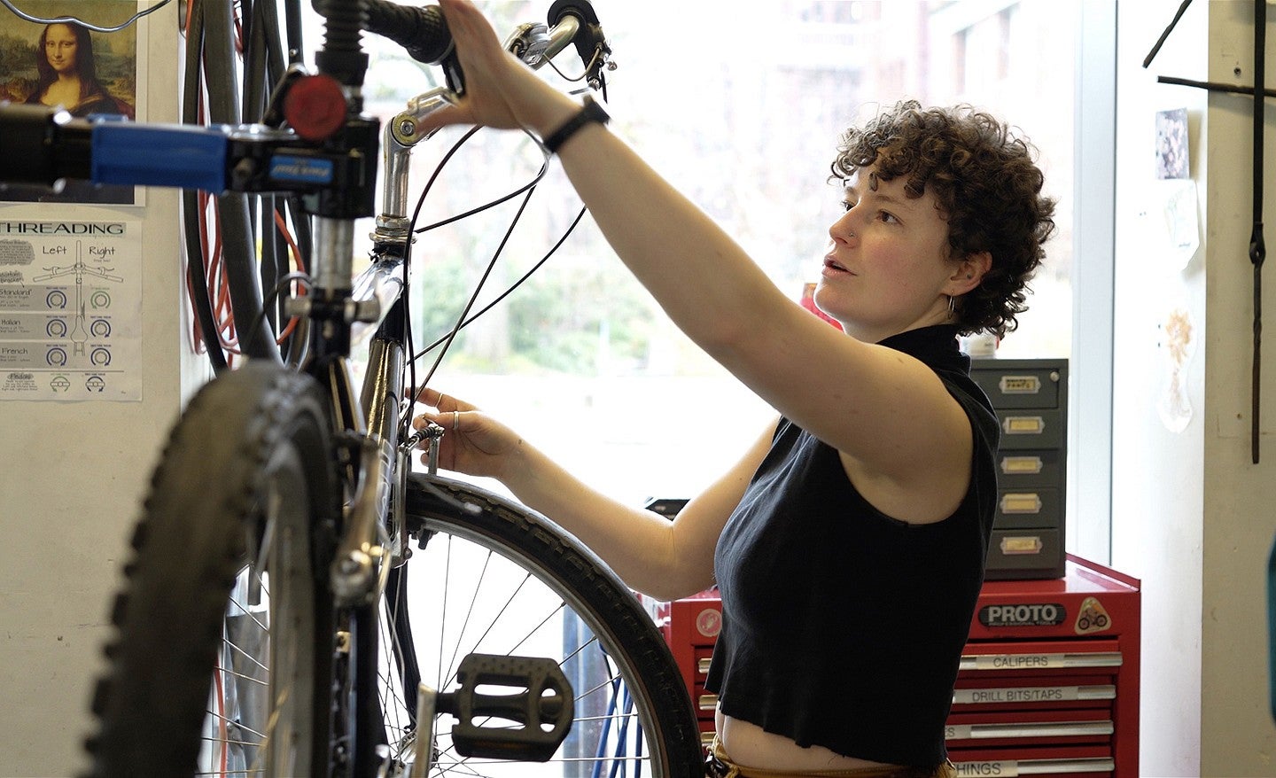 a woman standing in front of a bike on a repair stand, with her hands on the bike
