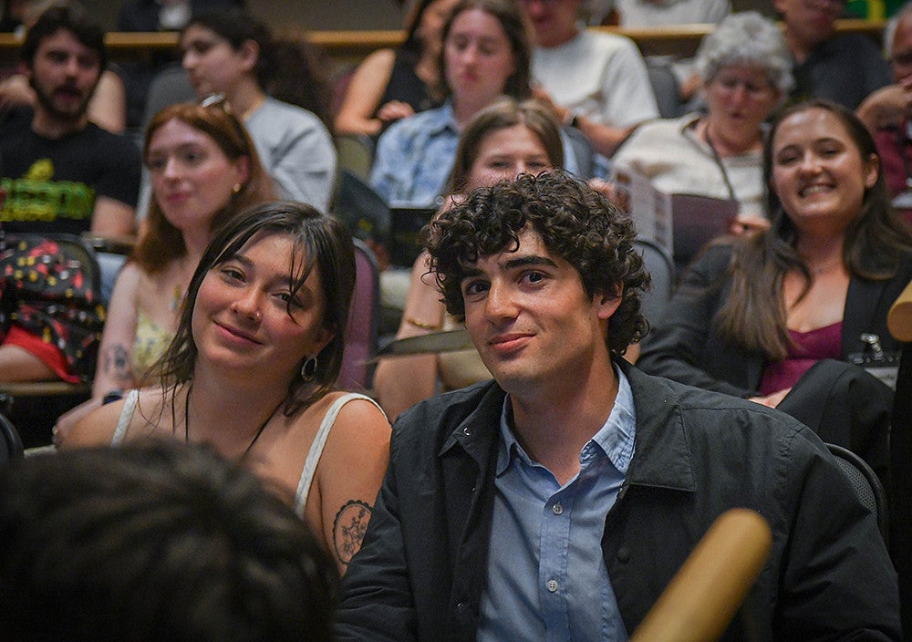 a presenter and friend sitting in audience at three minute thesis