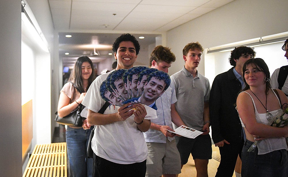 armaan hajar with photo signs depicting his brother auveen, winner of the three minute thesis competition