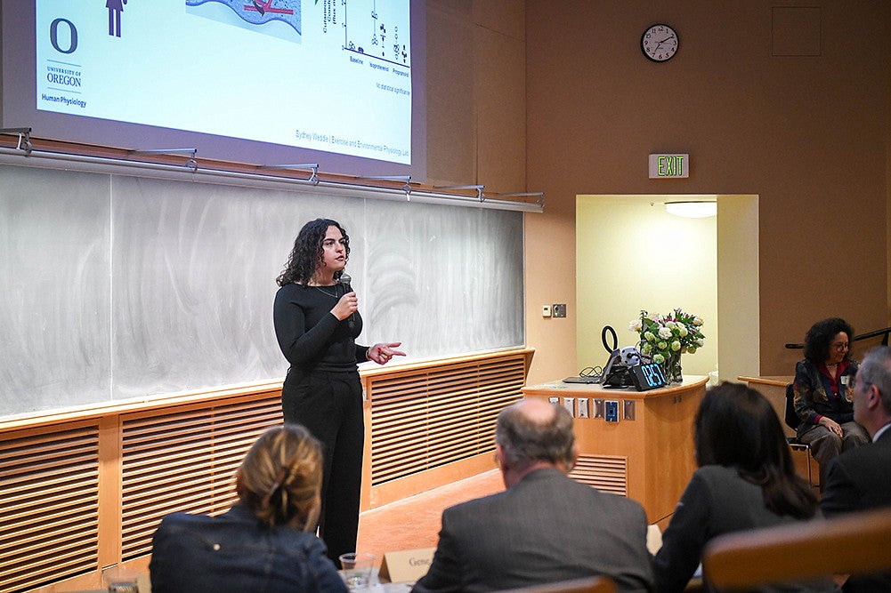 sydney weddle presenting under digital slide at three minute thesis competition