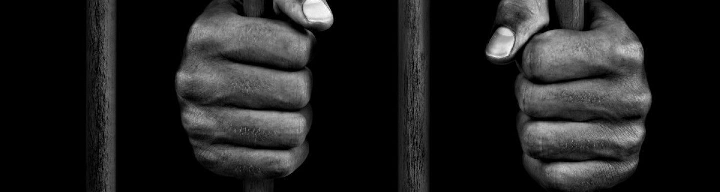 two hands gripping cell bars.