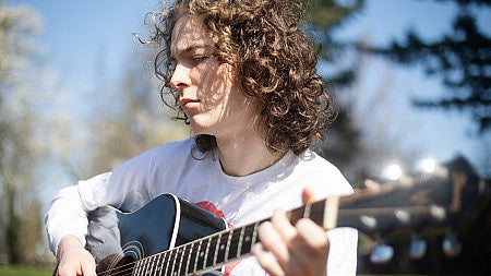Alex Goodwin playing a guitar.