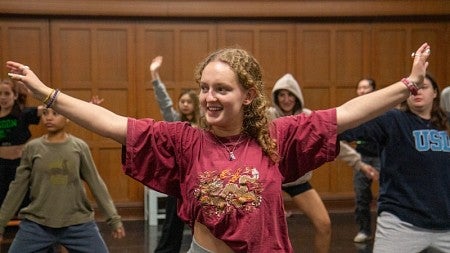 student in room of people dancing with outstretched arms