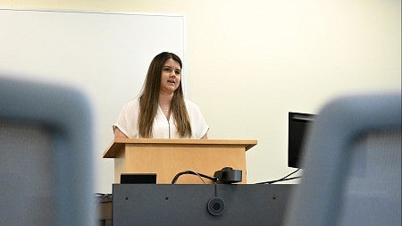 student at podium, speaking to empty classroom