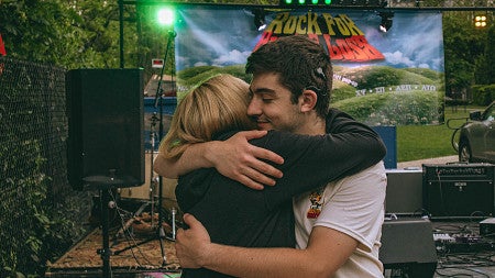 two people hugging in front of outdoor concert stage