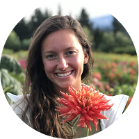 circular portrait of angela pelky holding a dahlia in a field of flowers