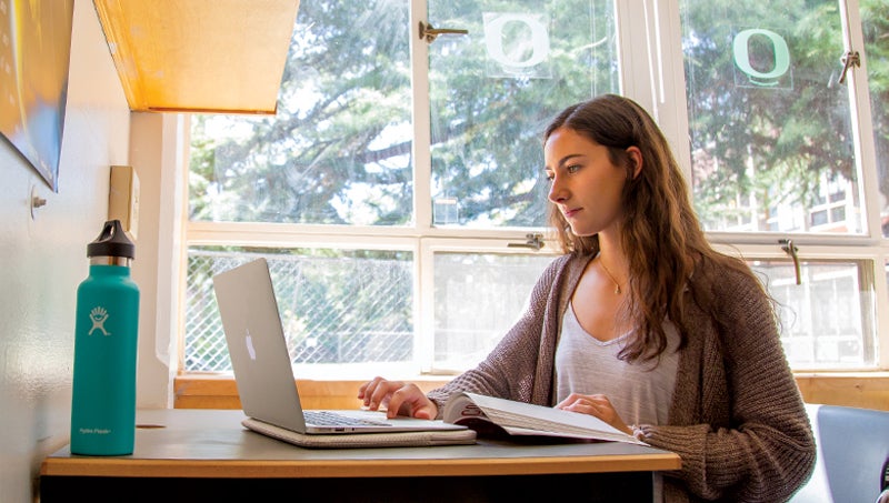 Student seated with notebook and laptop