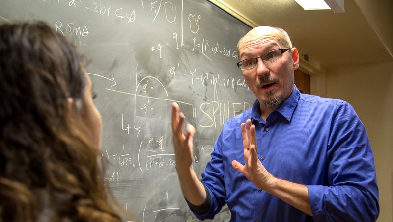 Instructor talking with student in front of chalkboard