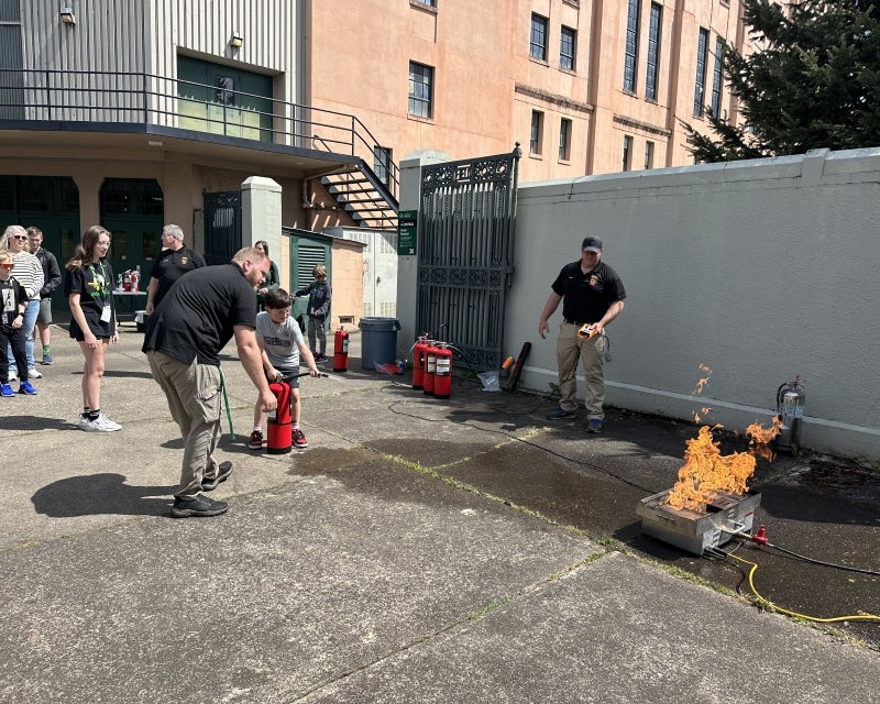 kid using fire extinguisher on a fire outside Mac Court