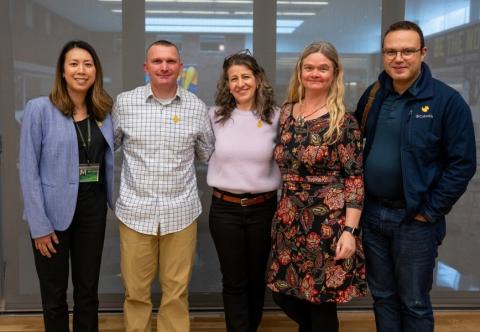 five people standing and smiling