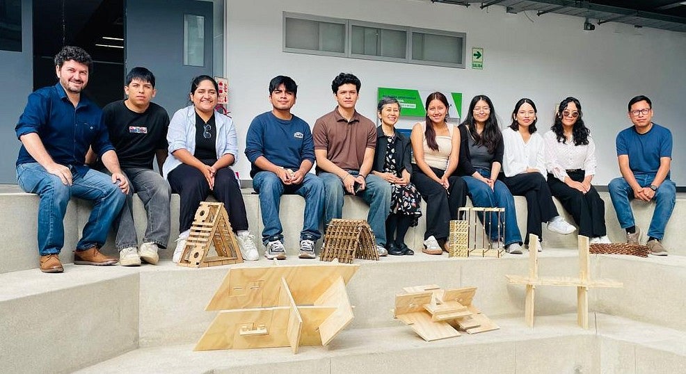Group of people sitting down in front of wooden structures