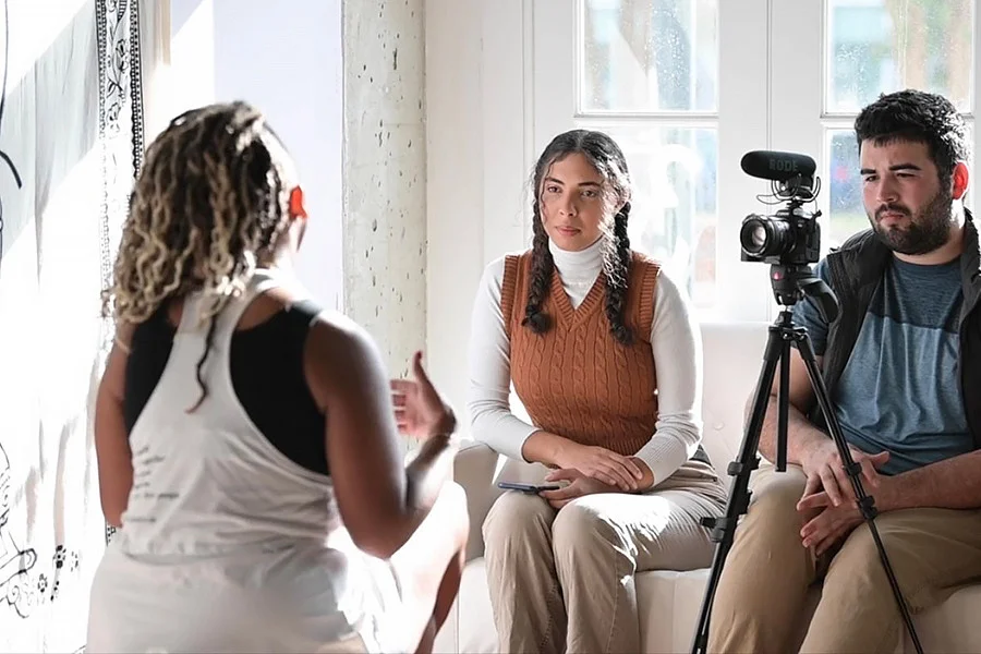 Jael Calloway sits with Canden Gutierrez as she interviews Adrianne Jackson, the owner of Magnolia Yoga Studio, for her story about the first black-owned yoga studio in New Orleans.