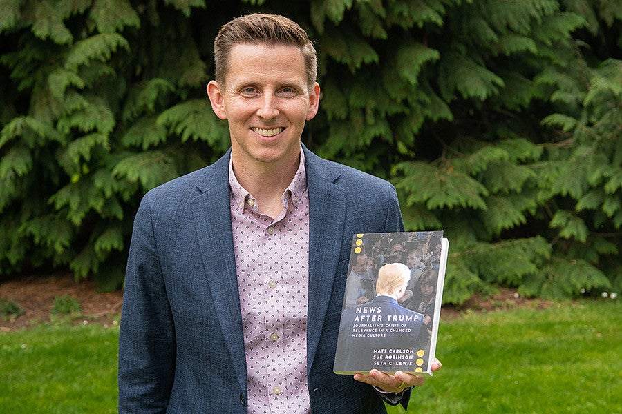 Seth Lewis holds a copy of his book "News After Trump"