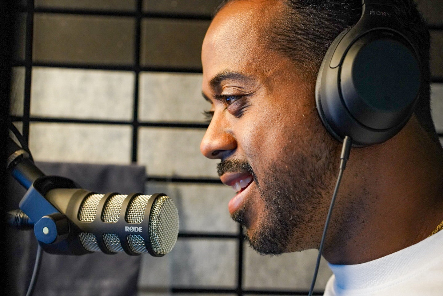 a close-up of Berto Jolliffe wearing headphones and speaking into a microphone in a recording studio