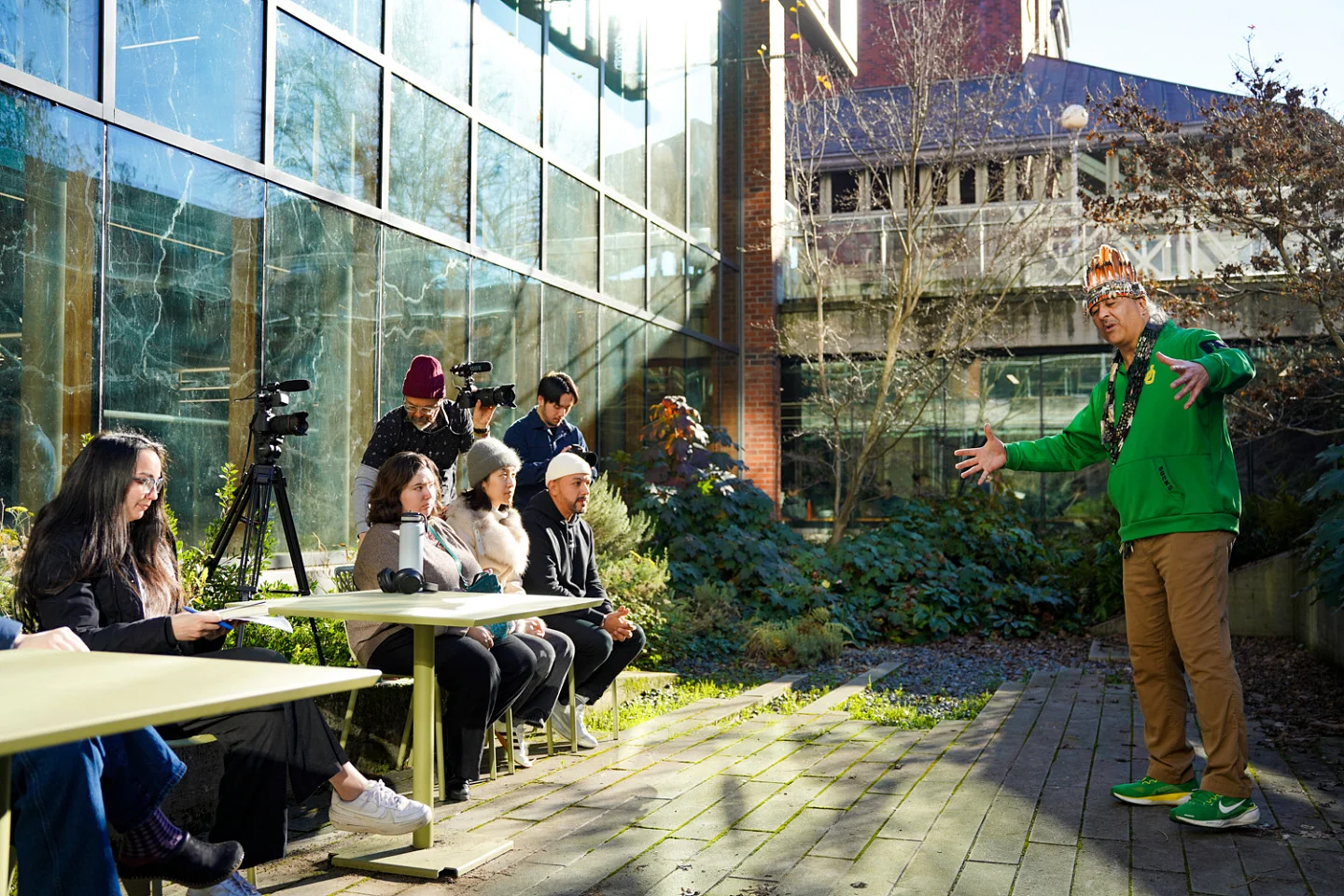 a group of people watch Jason Younker act out one of the stories of the Coquille Tribe in an outdoor courtyard