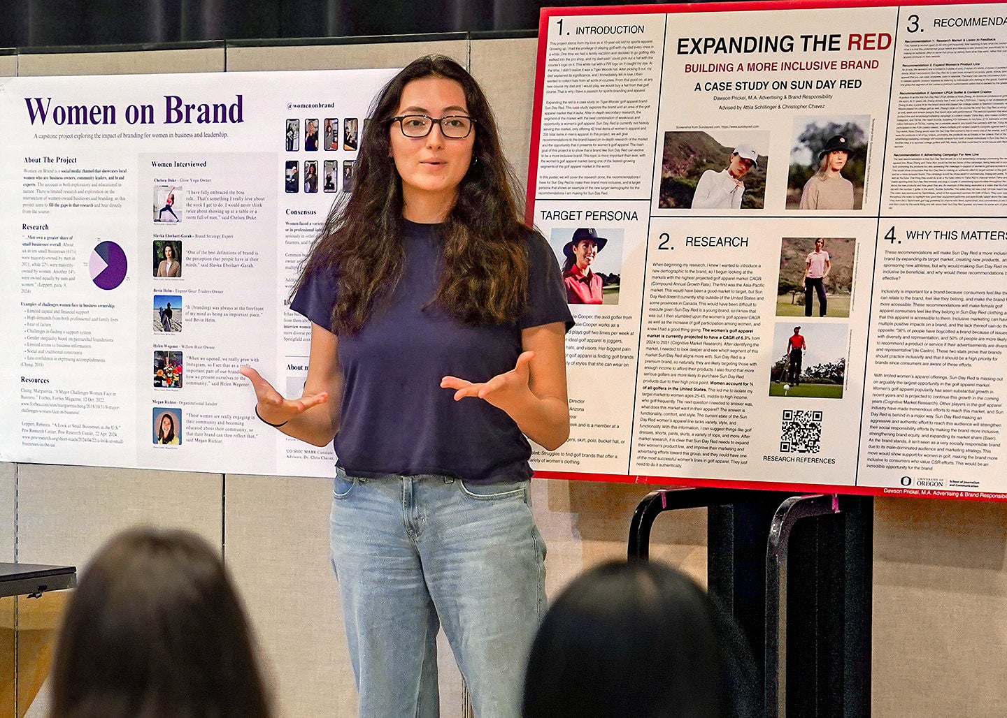 An advertising and brand responsibility master's student from the University of Oregon School of Journalism and Communication gives a presentation in front of capstone project posters