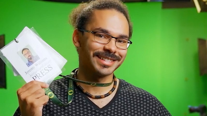 portrait of Jeremy Williams holding a press pass