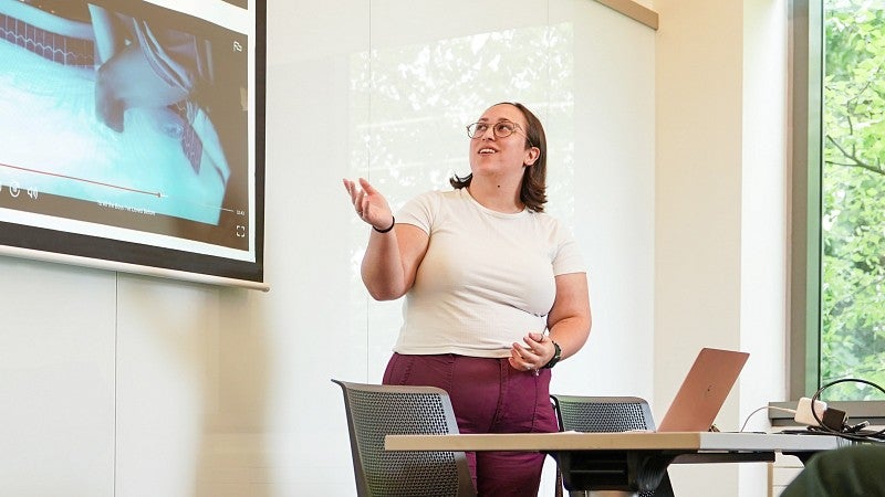 a student presents research in front of a digital screen