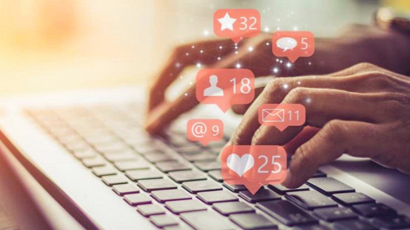 stock image of hands typing on a laptop with superimposed social media notification icons
