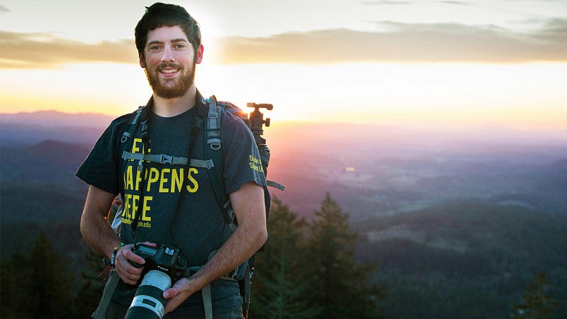 Justin Hartney standing on top of Spencer Butte holding a camera