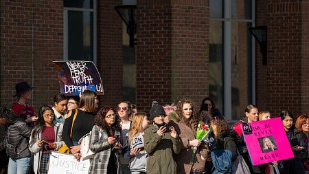 a group of supporters of Johnny Depp hold signs outside a large building
