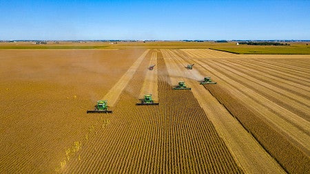 Farm machinery in a large field with a blue sky