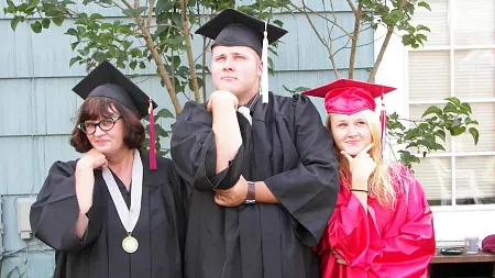UO Alumni Sharleen Nelson posing with her son and daughter in graduation gowns