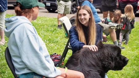 Alexis Weisend pets a large black dog while talking to its owner