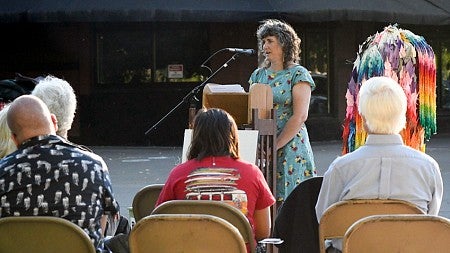 people sit at a news conference while a person speaks at a podium
