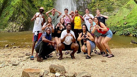 a group of SOJC students throw their Os in front of the Wli waterfall in Ghana