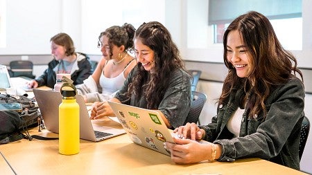 a group of SOJC using laptops at a classroom table