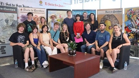 a group of students posed in front of large colorful posters