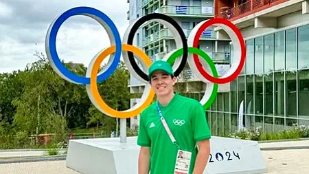 Austin Taylor poses in front of a large set of Olympics rings