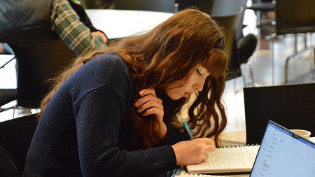 Chelsea Kropp leans over a notebook as she writes