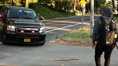 Cop car with lights on as person walks past