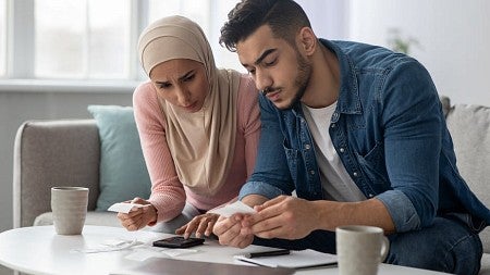 A man and a woman look over receipts and financial records in their living room.