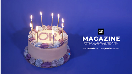 A white cake with burning candles sits in front of a purple background (photo credit Jassy McKinley).