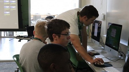 Multimedia journalism master’s student Jeff Collet helps a student in assistant professor Ed Madison’s “NextGen Storytellers” class.