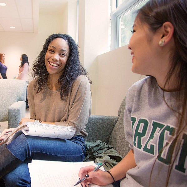 two students sit and laugh while studying