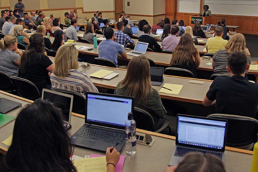 Students in large classroom with laptops open. 