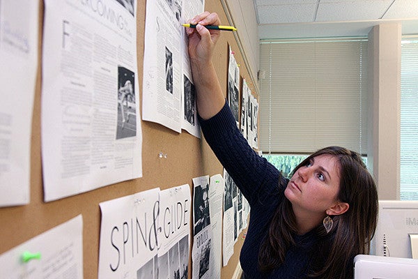 person making notes on documents taped to a wall