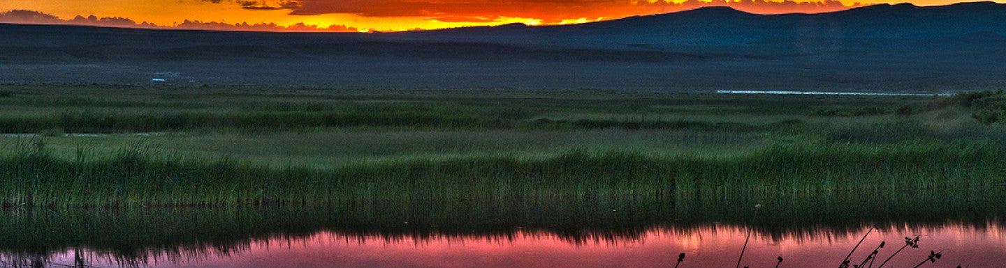 sunset behind mountains reflected on the water