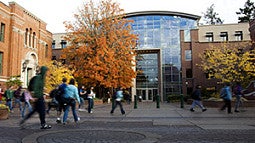 students walking across courtyard with fall-colored trees